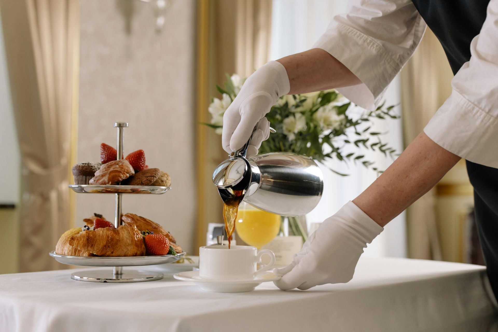 Luxurious breakfast scene with fresh pastries, coffee being poured, and elegant table setting.